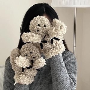 Détail de gants patte de chiot en peluche crème avec nœuds noirs et texture en fausse fourrure