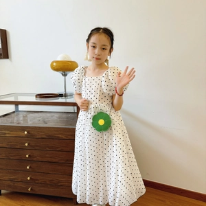 Cute green sunflower shaped kids shoulder bag worn by a girl in polka dot dress