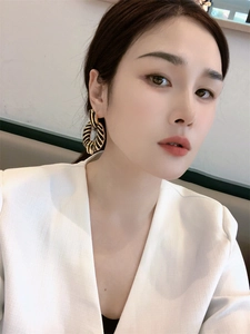 Close-up of model wearing 18K gold zebra pattern hoop earrings with black enamel wrap