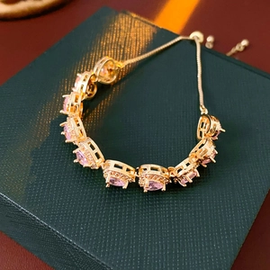 Macro detail of gold-plated double-layer heart bracelet with pink cubic zirconia stones