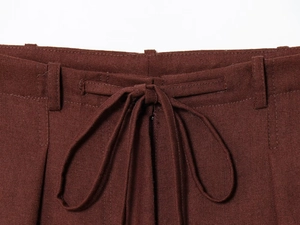 Detail of dark brown trousers waist featuring drawstring and high-quality fabric texture