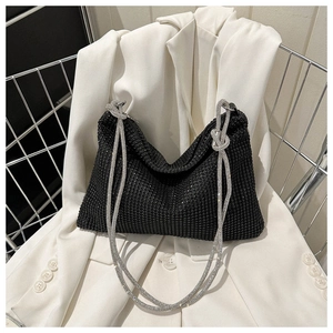 Detail of hobo bag with black crystals, knotted strap and white rhinestones on a white blazer