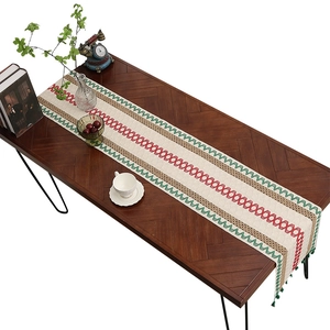 Vintage Christmas table runner with red and green embroidery and tassels on wood table