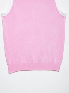Gros plan du gilet en maille rose montrant les coutures et l'ourlet côtelé