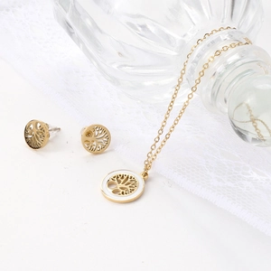 Close-up of golden Tree of Life jewelry set including necklace and earrings on lace