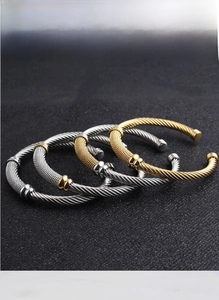 Detail view of woven mesh 18K gold and silver stainless steel cable C-shaped cuff bracelets