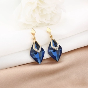 Close-up of elegant gold drop earrings featuring blue geometric crystals and white zircons