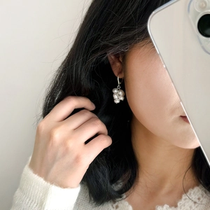 Detailed view of natural freshwater pearl cluster earrings on a model silver hoop