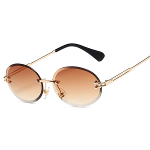 Frameless oval sunglasses with brown gradient lenses and gold metal temples on white backdrop