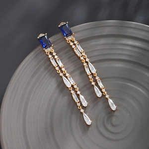 Macro detail of luxury gold earrings with blue rectangle gemstones and cz fringe tassels