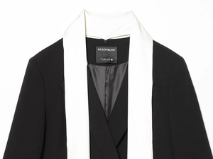 Détail du revers châle en satin contrasté sur un blazer noir avec étiquette de col