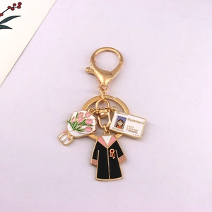 Detailed close-up of golden graduation keychain with enamel gown and bouquet pendants