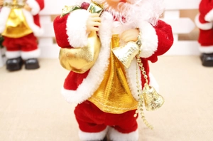Detail of plush Santa figure holding golden bells and a gift bag for holiday decor