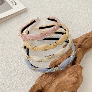 Detail of woven fabric headbands with gold chains and sparkling crystal beads on driftwood