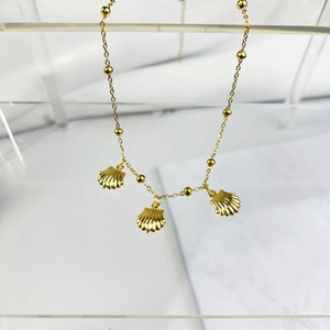 Detail shot of a gold-plated necklace featuring three scallop shell pendants and beads