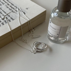 Minimalist 925 sterling silver necklace featuring three-ring pendant on a vintage book