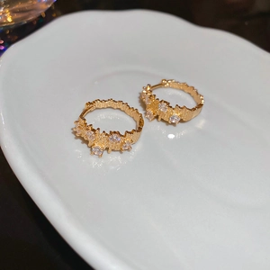 Macro shot of gold hammered earrings featuring textured finish and sparkling zircon stones