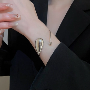 Polished silver teardrop cuff bracelet with small ball end worn on a female wrist