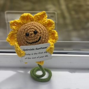 Detailed view of a handmade crochet sunflower doll with an optimistic message card