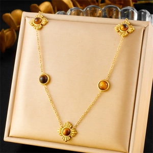 Close-up of gold stainless steel necklace with clover-shaped tiger eye stones in jewelry box