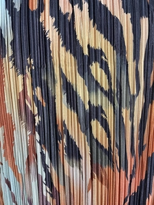 Close-up of pleated animal print fabric with leopard pattern in brown and beige tones
