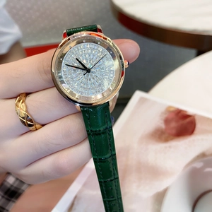 Close-up of rose gold watch with diamond dial and dark green leather strap on wrist