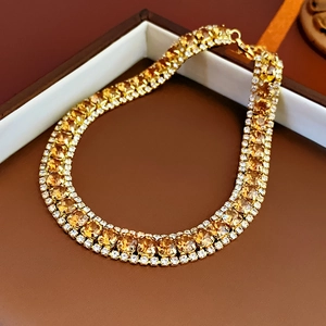 Detailed close-up of golden necklace with yellow square crystal and pavé rhinestones