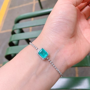 Close-up of a silver bracelet with a square green gemstone and sparkling diamond accents