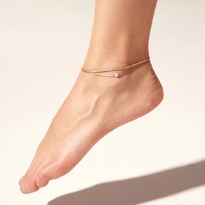 Detail of a double-layered gold stainless steel anklet with a delicate white pearl