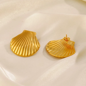 Boucles d'oreilles coquillage en acier plaqué or 18K présentées sur du tissu en soie