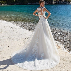 Elegant white lace wedding dress with an open back design and grand circular train at beach