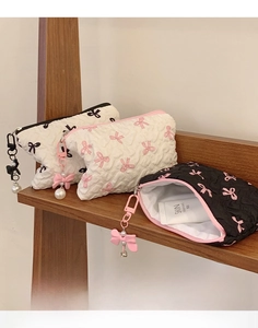 Quilted bow makeup bags with heart patterns and pearl charms on a wooden display