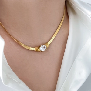 Detail of gold snake chain necklace with an oval cubic zirconia on model's neck