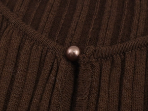 Detailed macro view of dark brown ribbed knit fabric with a matching pearl button closure