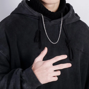 Detail shot of a silver twisted rope chain necklace worn on a washed black hoodie