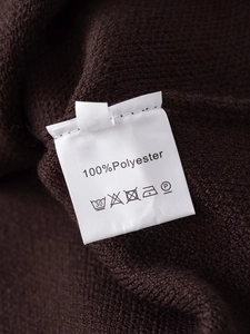 Détail du tissu tricoté marron en 100% polyester avec étiquette d'entretien de lavage