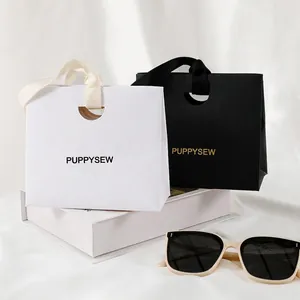 Elegant paper gift bags in black and white with satin handles and gold foil printing