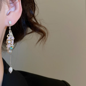 Detailed close-up of crystal tassel earrings with colorful gemstones and a white pearl drop