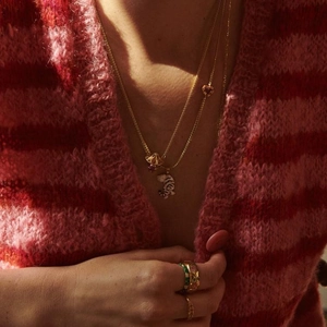 Golden heart necklace and 3D tiger pendant set shown on a model with knitwear