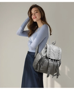 Detailed view of gray washed leather backpack with silver rivets on model back