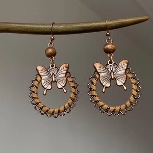 Detailed close-up of retro butterfly earrings with wooden beads and bronze hollow frame