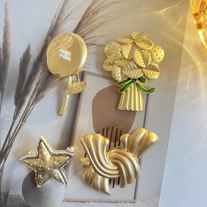 Détails de quatre broches vintage en or mat aux formes de fleurs et de coquillages