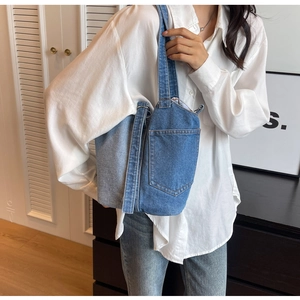 Detail of blue patchwork denim shoulder bag with front pocket shown on a model