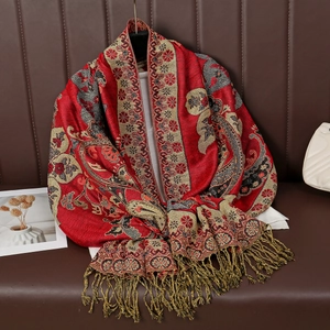 Nahaufnahme des roten Ethno-Schals mit Paisley-Muster und goldenen Fransen auf Ledersofa
