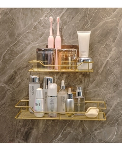 Close-up of golden wall-mounted bathroom shelves with metal wire frame on marble wall