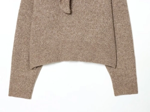 Détail d'un pull en maille marron clair avec ourlet droit et poignets côtelés