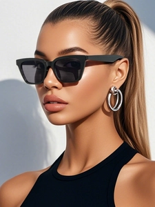 Detail of vintage cat-eye sunglasses and silver hoop earrings on a fashion model