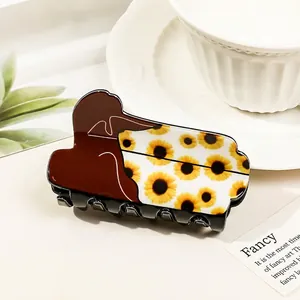 Detail of hair claw clip with sunflower print and woman silhouette on white bowl