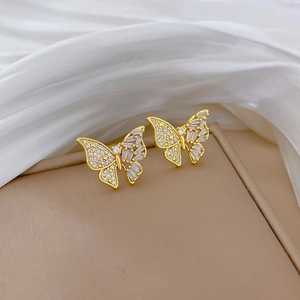 Gros plan de boucles d'oreilles papillon dorées avec zircons brillants sur fond de soie