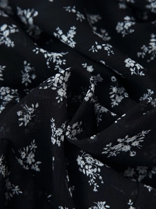 Gros plan sur le tissu en mousseline noire avec motif floral blanc et texture fine
